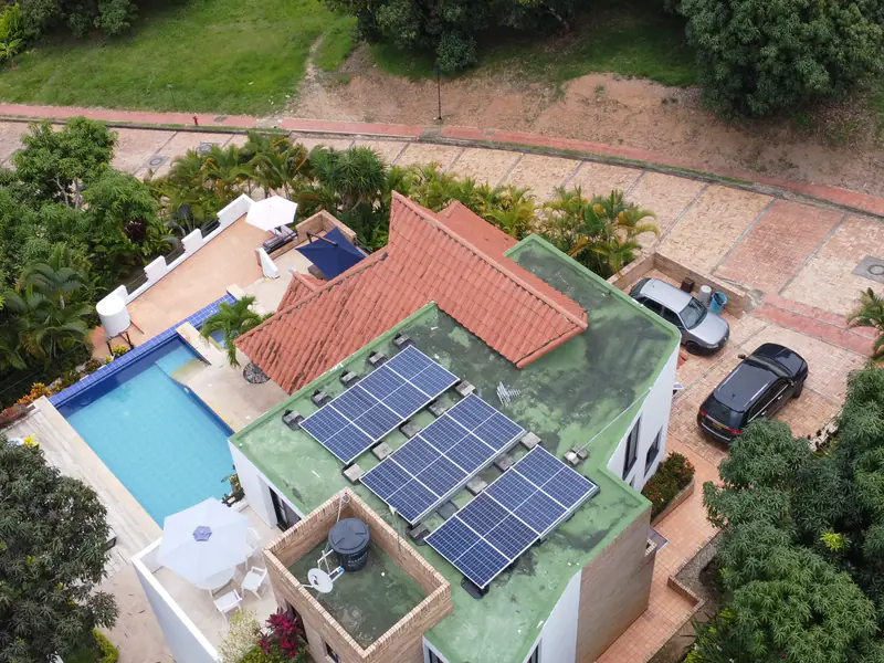 Vista aérea de una casa en Anapoima, Cundinamarca, con paneles solares sobre la terraza, junto a la piscina