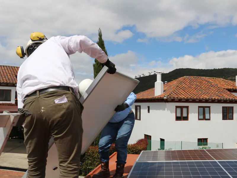 Dos técnicos con casco y guantes montan un panel solar sobre una cubierta de teja en Chía, Cundinamarca